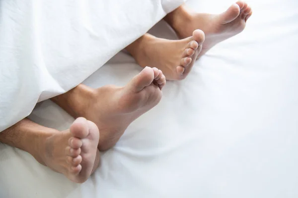 Close-up van paar Barefoot onder deken in de slaapkamer in honeymoo — Stockfoto