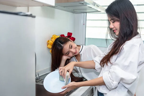 Två asiatiska kvinnor tvätta rätter tillsammans i köket. Människor och L — Stockfoto