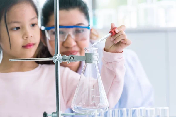 Scientist girl and teacher dropping solution substance liquid wi — Stock Photo, Image