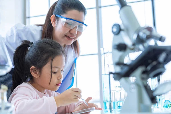 Scientist girl and teacher dropping solution substance liquid wi — Stock Photo, Image