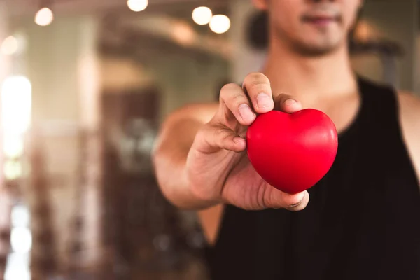 Buon uomo sportivo con il cuore rosso in palestra fitness club. Medico c — Foto Stock