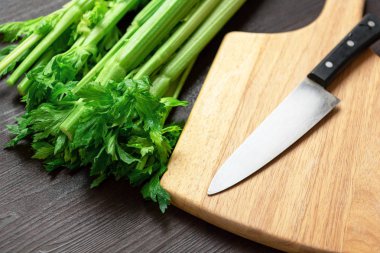 Ahşap masa ve kesme tahtası üzerinde taze kereviz sapı Demet bir