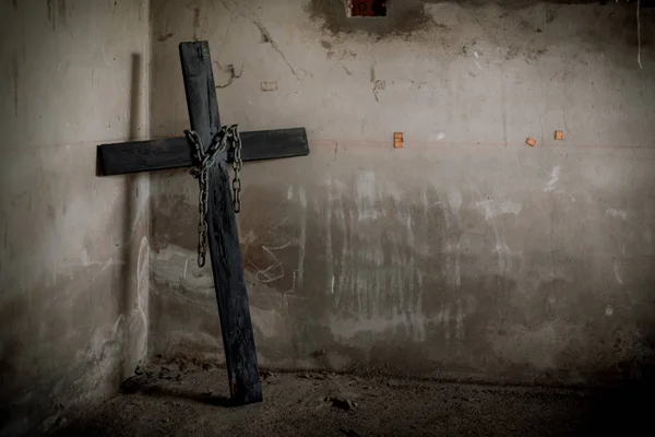 Crucifix noir contre mur avec chaîne en acier suspendue et pistolet. Ha ! — Photo