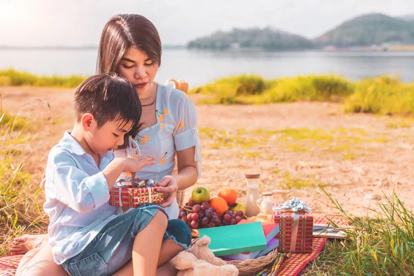 Красивая азиатская мать и сын делают пикник и открывают подарочную коробку — стоковое фото