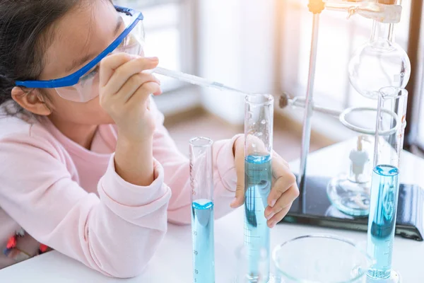Azjatycki dziecko chemik trzymanie kolby i probówki w rękach w laboratorium — Zdjęcie stockowe