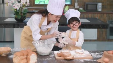 Güzel kadın ve gözlük, şef şapka ve önlük oynayan ve ev mutfağında fırın pişirme komik ile sevimli küçük Asyalı çocuk. Ev yapımı yemekler ve ekmek. Eğitim ve öğrenme kavramı. Taylandlı kişi