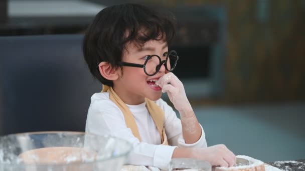 かわいいアジアの男の子のメガネとエプロンが遊んで シェフとして家庭の台所でパン屋を焼く面白い 自家製の食べ物とパン 教育と学習の概念 肖像画と夢の仕事の職業 — ストック動画