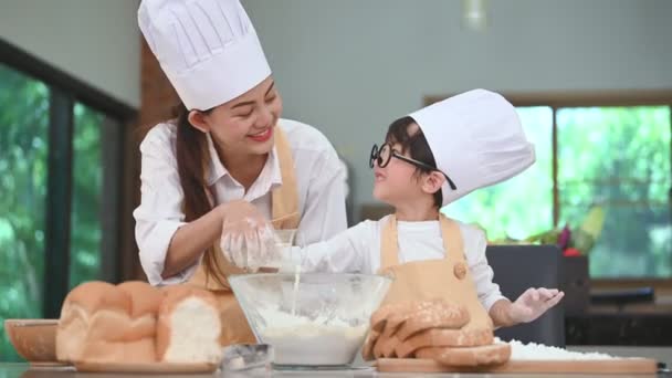 美しい女性とかわいいアジアの少年とメガネ シェフの帽子とエプロンは 家庭の台所で牛乳を注ぎ パン屋を焼く面白いです 自家製の食べ物とパン 教育と学習の概念 — ストック動画