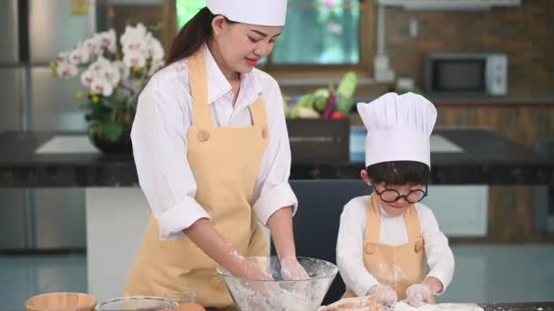 美しい女性とかわいいアジアの少年とメガネ シェフの帽子とエプロンの遊びと家庭の台所でパン屋を焼く面白い 自家製の食べ物とパン 教育と学習の概念 タイ人 — ストック動画