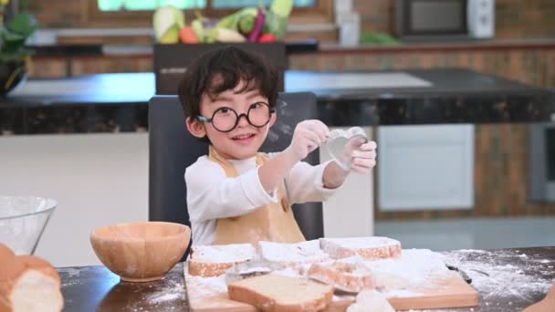可爱的亚洲小男孩与眼镜和围裙玩和烘焙面包店在家庭厨房作为厨师有趣 自制食品和面包 教育和学习理念 肖像和梦想工作职业 — 图库视频影像