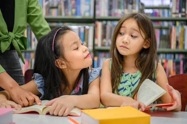 Duas meninas bonitos estão com ciúmes um do outro enquanto lendo livros em — Fotografia de Stock