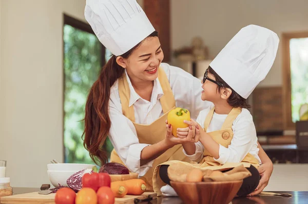 Feliz familia asiática en la cocina. Madre e hijo en sombrero de chef prepar — Foto de Stock
