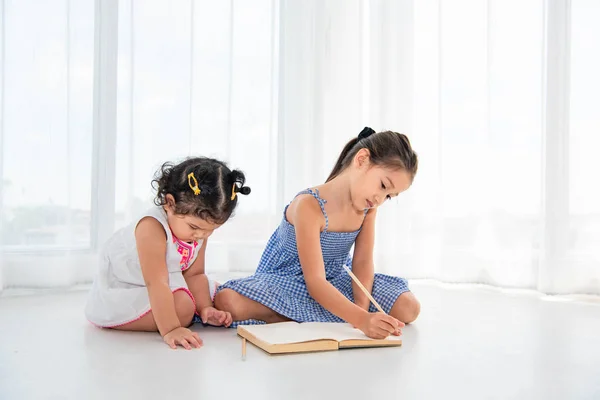 Happy two sister drawing in sketch book together at home or nurs — Stock Photo, Image