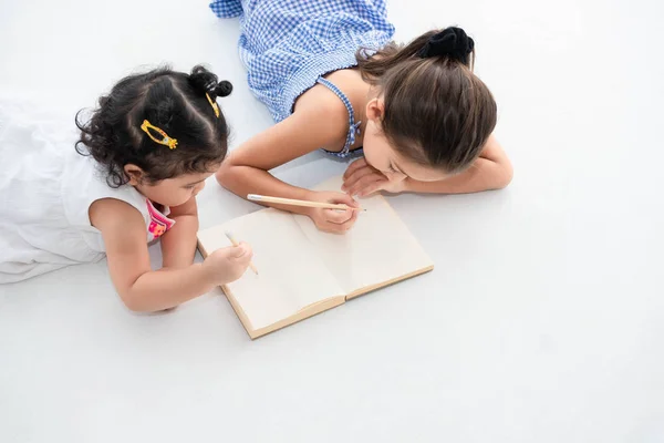 Top uitzicht van gelukkige twee zus tekening in schetsboek samen op — Stockfoto