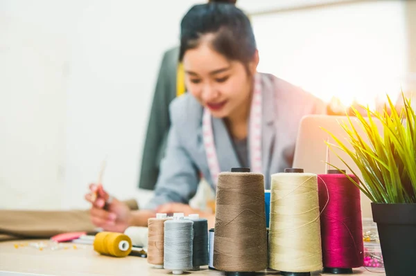 Close up of color thread with blurry happy female tailor and sewi — стоковое фото