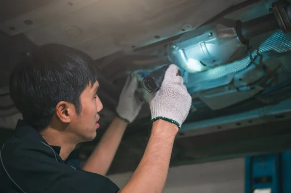 Asiatique mâle mécanique tenir et brillant lampe de poche pour examiner la voiture — Photo