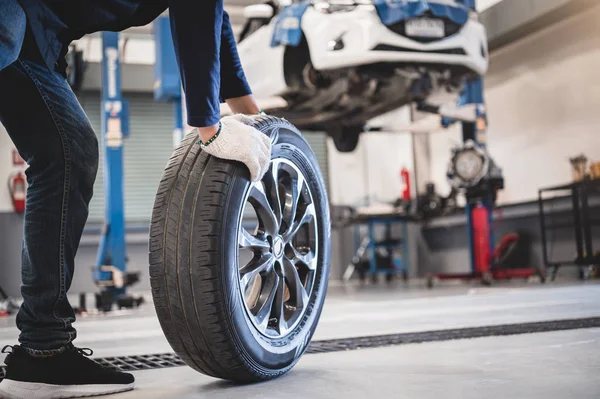 Mechaniker halten und rollen Reifen in Werkstatt — Stockfoto