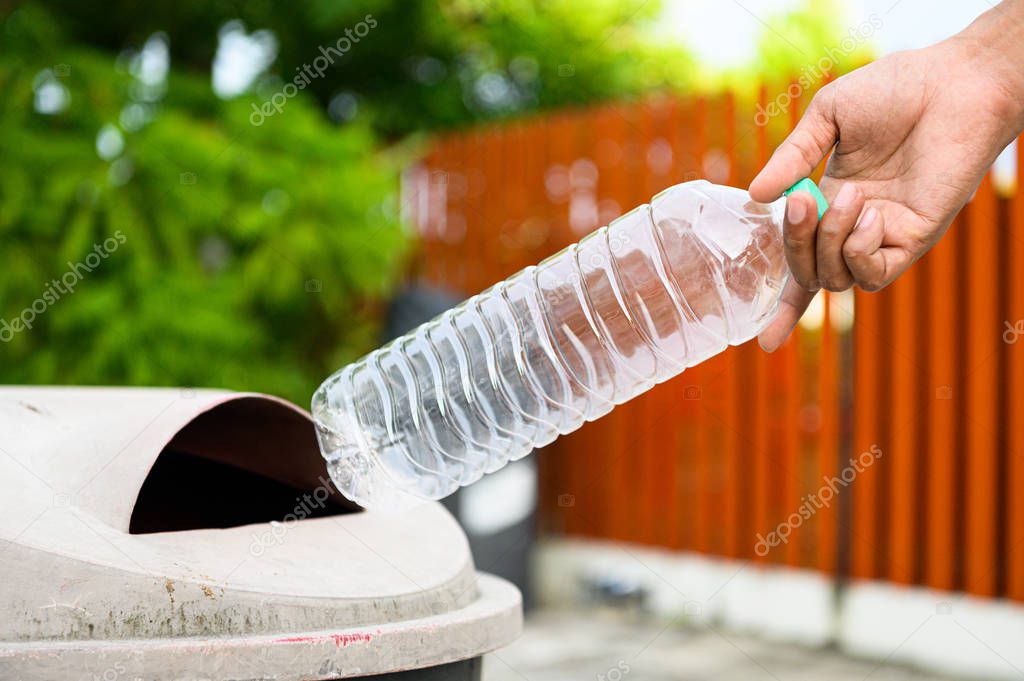 Closeup of hand throwing away empty plastic bottle into trash fo