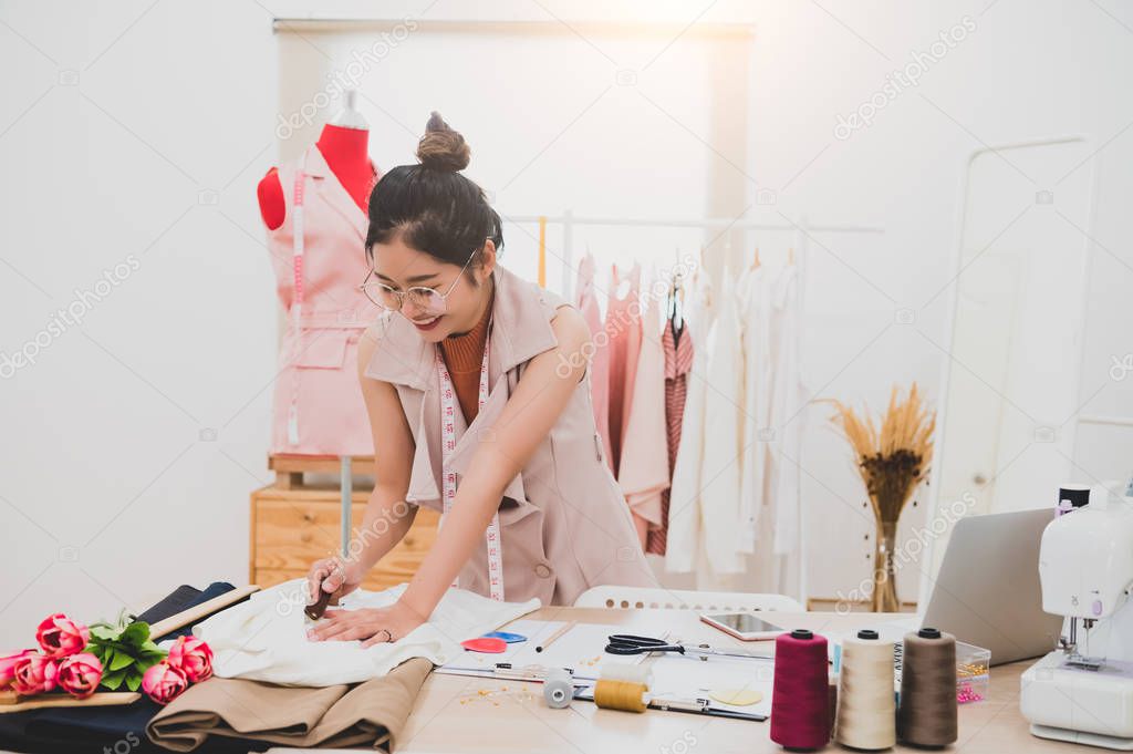 Attractive Asian female fashion designer working in home office 