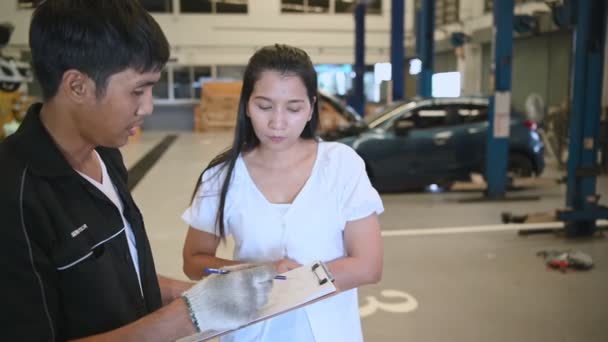 車のサービスで女性の顧客と話す修理工の映像 — ストック動画