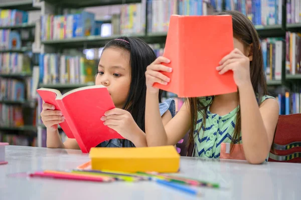 Duas meninas bonitos multi-étnicos amigos lendo livros juntos — Fotografia de Stock