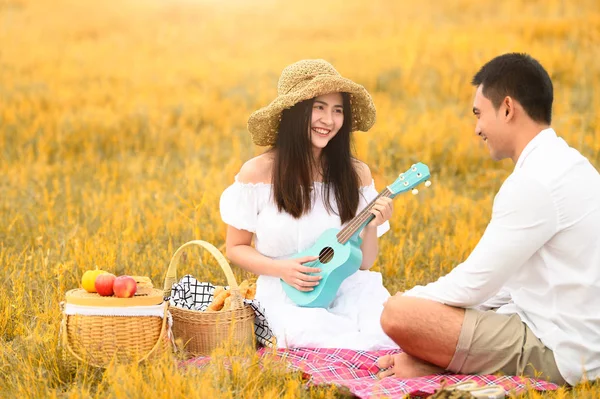 秋の草原のフィールドで2人のアジアの若いカップルがhでピクニックをしています — ストック写真