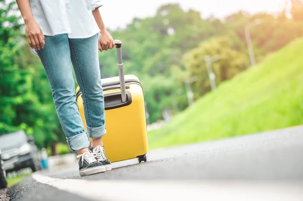 Nahaufnahme Unterkörper einer Frau, die mit gelbem Rollkoffer hantiert — Stockfoto