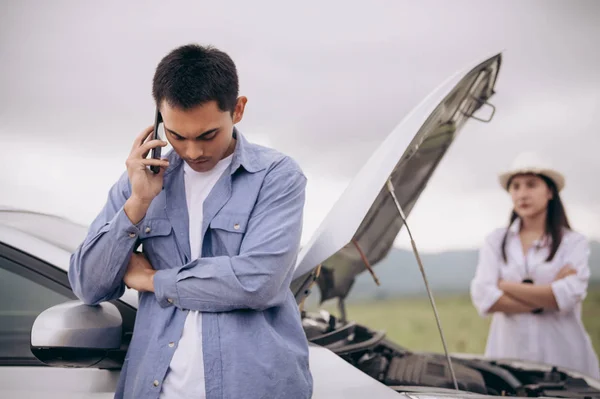 Asiatisch mann calling auto wartungsdienst mit seine freundin lo — Stockfoto