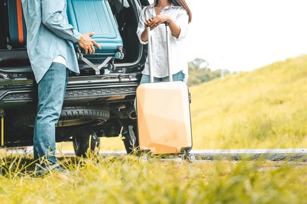 Closeup lower body of couple lift down trolly luggage at back of