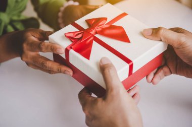 Noel günü kırmızı kurdeleli hediye kutusu ve yeni yıl festivali için el ele tutuşuyoruz. Erkek kadına sürpriz yapıyor. Tatil ve etkinlik. Yıl sonu partisinde çıkma konusunda şaşırtıcı bir hediye kutusu