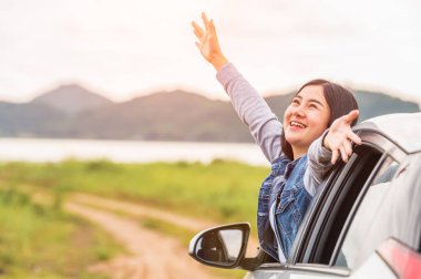 Mutlu Asyalı kadın gün batımının altında kollarını açtı. Tatil sırasında deniz kenarında doğayla iç içe. Şafak vakti gökyüzüne sahip kendine güvenen neşeli kız. Güneş denizi ve dağ. Tatil kavramı