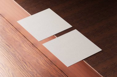 Beyaz kare kağıt kartvizit modeli ahşap kahverengi masa arka planında. Marka sunumu şablon baskı grafik tasarımı. İki kart birbirini tamamlıyor. 3B illüstrasyon oluşturma