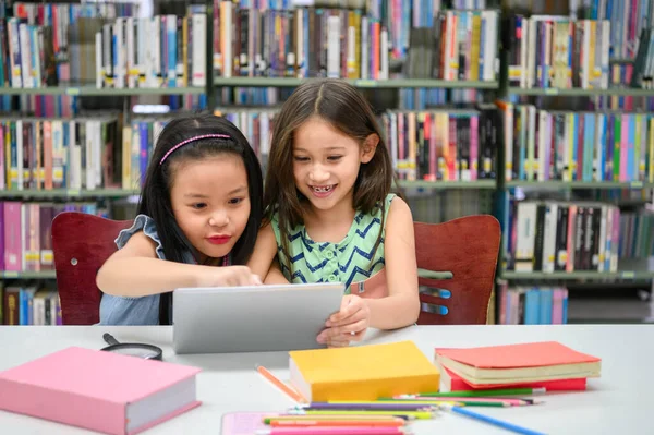 Dwie Małe Szczęśliwe Słodkie Dziewczynki Grające Tablecie Bibliotece Szkole Edukacja — Zdjęcie stockowe