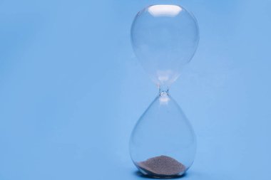 Zamanı ölçmek için mavi arka planda kum bulunan saat camı