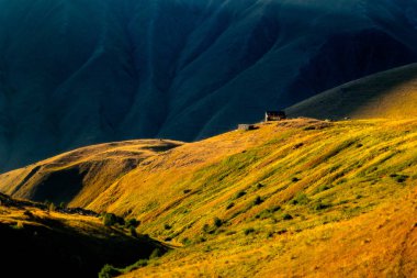 Dağ çayır ve kulübe Kafkasya'da Kazbegi Milli Parkı, ülke Gürcistan ile renkli günbatımı