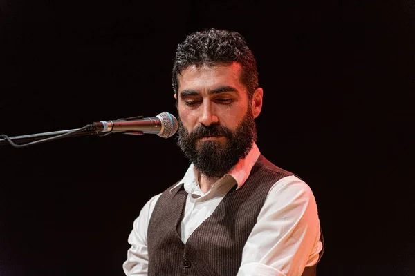 Good-looking man with thick black beard, musician plays on stage
