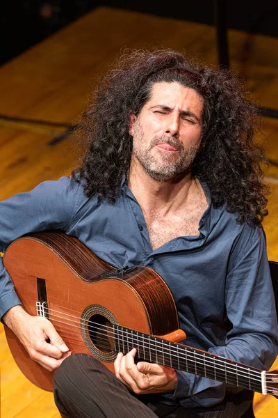 handsome man with long hair playing classical guitar