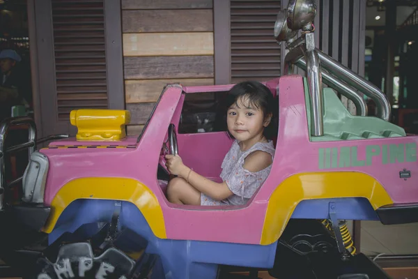 little girl learns to drive the toy car