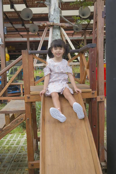 可爱的亚洲小女孩有乐趣玩木滑梯 — 图库照片