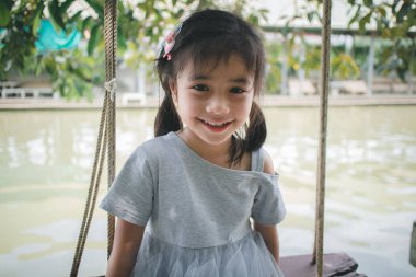  küçük kız açık salıncakta eğleniyor