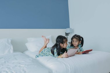 Yatakta oyun oynayan iki küçük kız kardeş.