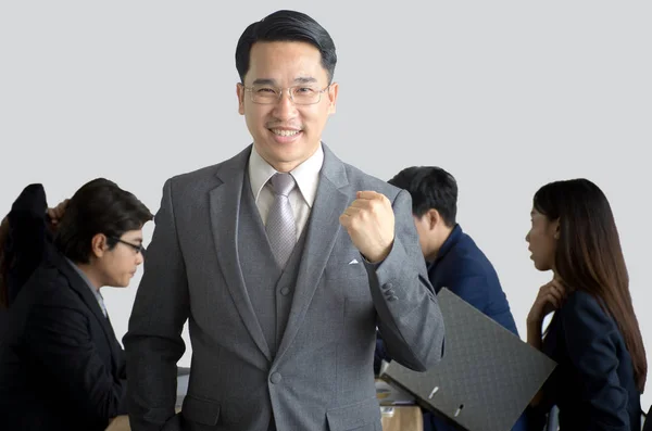 Portrait of smiling businessman standing in front of team with arms up celebrating at office,Asian Businessman leading her team isolated over a gray background, team work concept