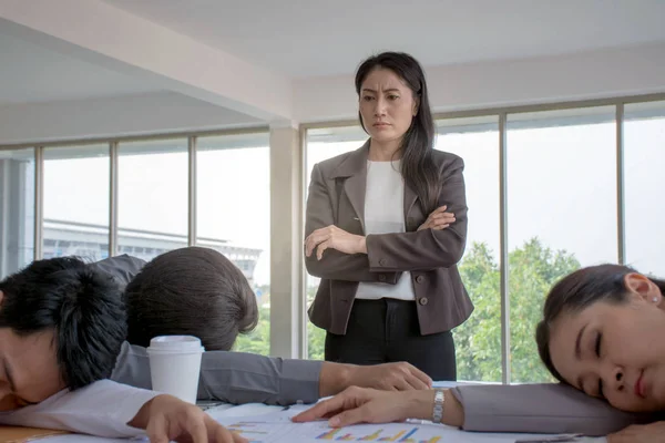 Picture of angry Asian boss watching employees sleeping in the office because overworked with too much