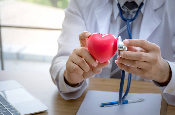 Close up of doctor with stethoscope examining red heart, Health concept
