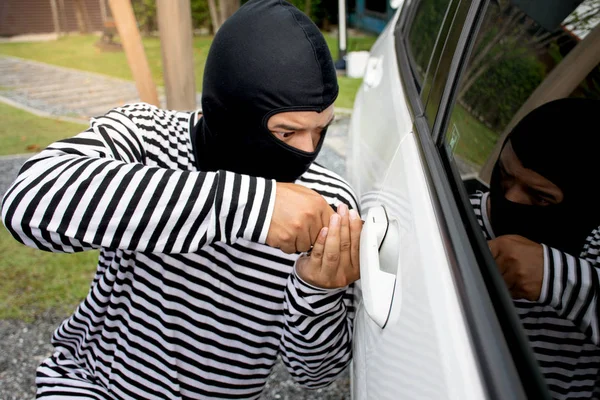 男人强盗与巴拉克试图闯入车他头上 他用螺丝起子 选择性焦点 刑事和车贼概念 图库照片