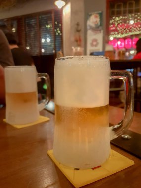 İki soğuk cam ahşap bar sayacı ile bulanık pub arka plan/seçici odak bira