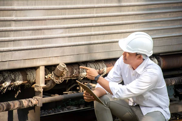 亚洲工程师戴安全帽 检查列车维修的图片 图库图片