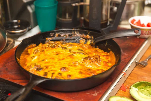 Taze enchiladas veya burrito biber sos ve peynir bir dökme demir tavada kaplı. Ev mutfak ayarı.