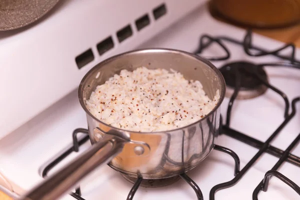 Pot of rice cooking on gas stovetop or burner. Rice is seasoned.