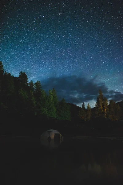 Starry night sky over small dome structure in hot spring pool. Bright night sky seen from the Dark Sky Corridor in Idaho, USA.